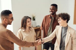 Quatre collègues souriant et se serrant la main dans un bureau lumineux.