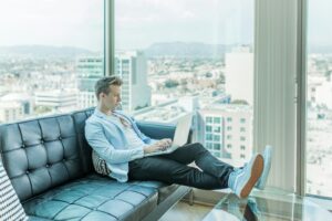 homme assis sur un canapé tout en utilisant un ordinateur portable
