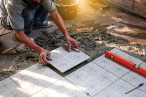 Pose méticuleuse de carreaux à motifs par un bon carreleur à Belley sur un lit de mortier frais